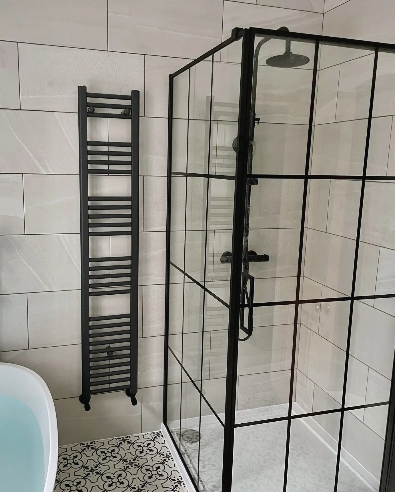 Black-framed shower enclosure beside a tall towel radiator