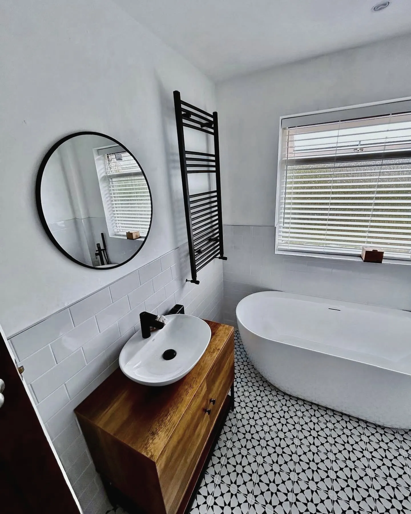 Bathroom with a countertop basin on a timber vanity, a round mirror and a freestanding bath